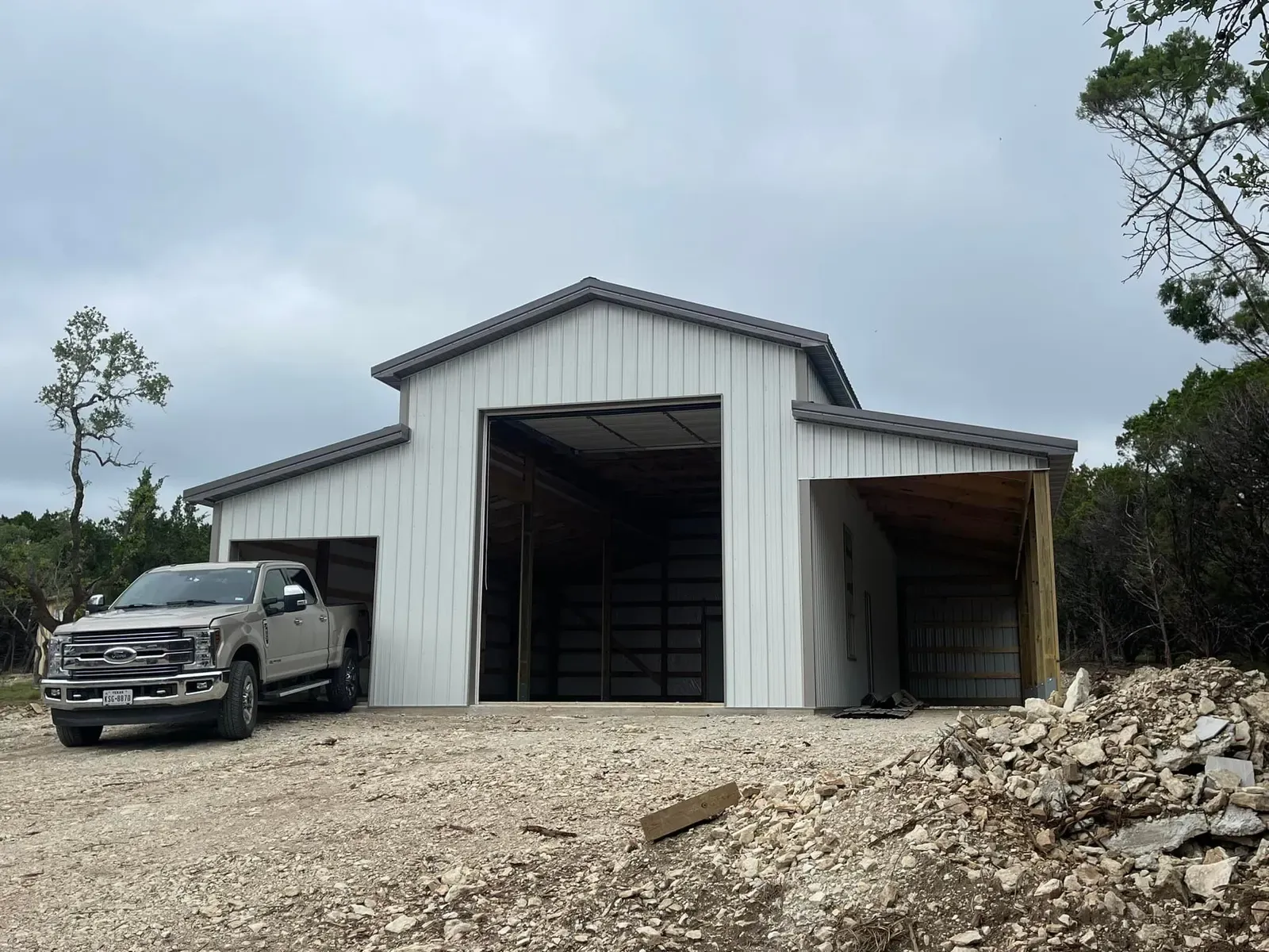 A white steel RV barn with a tall center bay and lean-tos on both sides in Texas