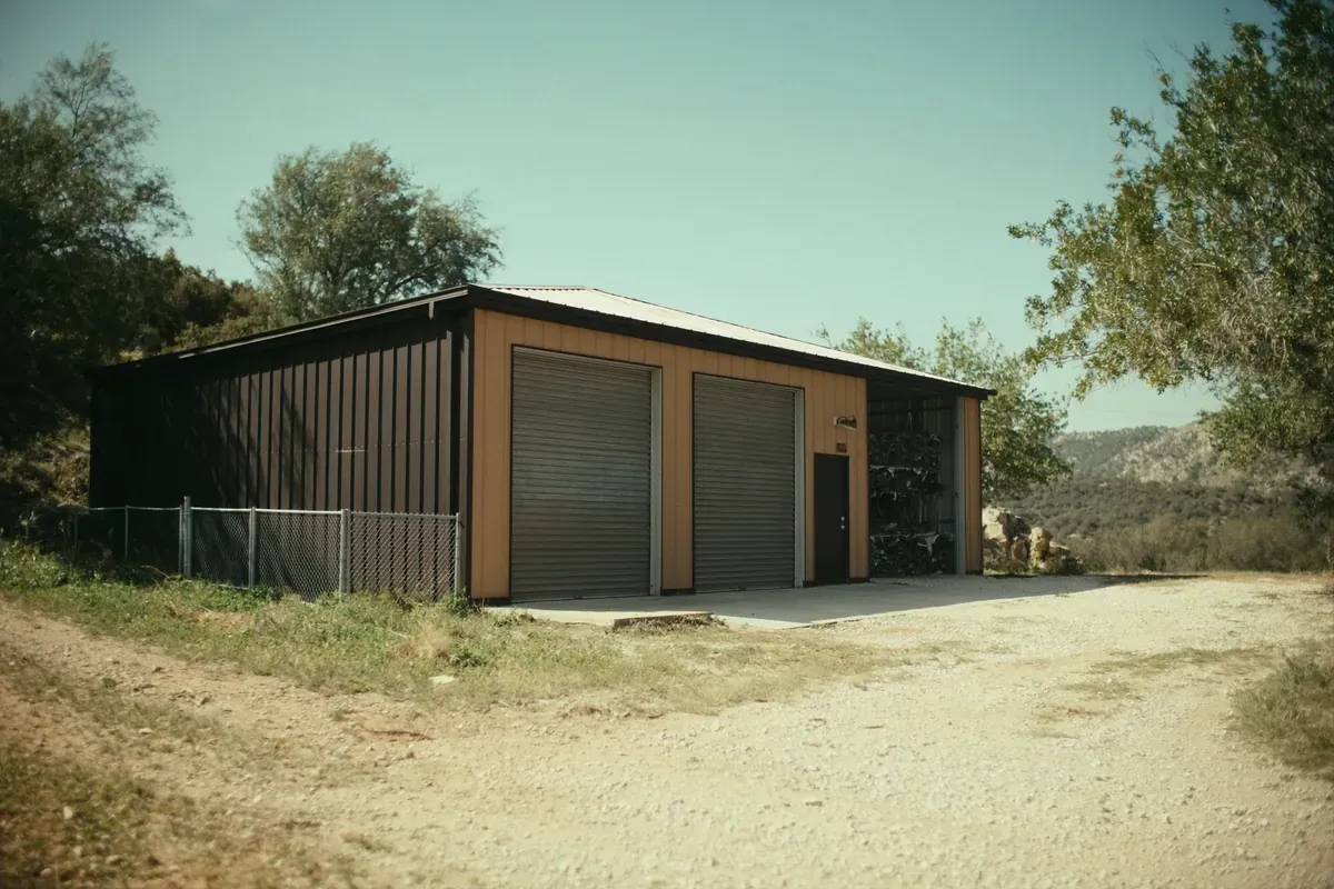 A metal shop building with two roll-up doors in the Texas Hill Country
